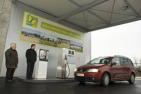 Two men and a car in front of a biogas plant.