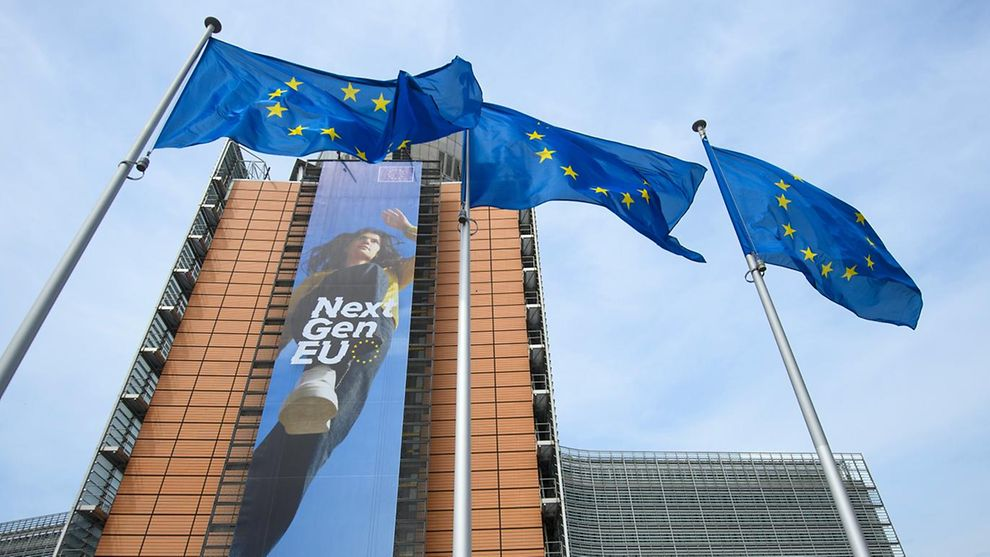 NextGenEU Banner mit Frau auf einem Hochhaus und davor stehen drei Fahnenmasten mit der EU Fahne.