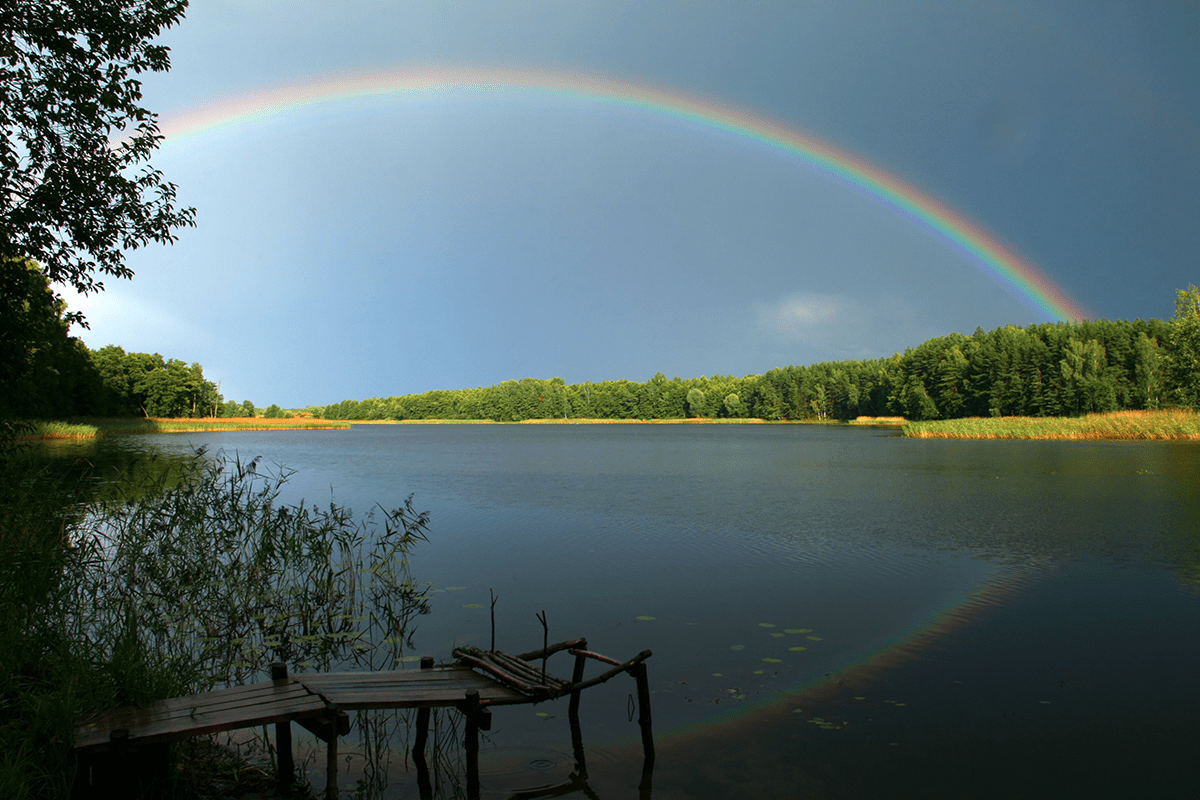 Rainbow stretching from one shore to another over a calm lake
