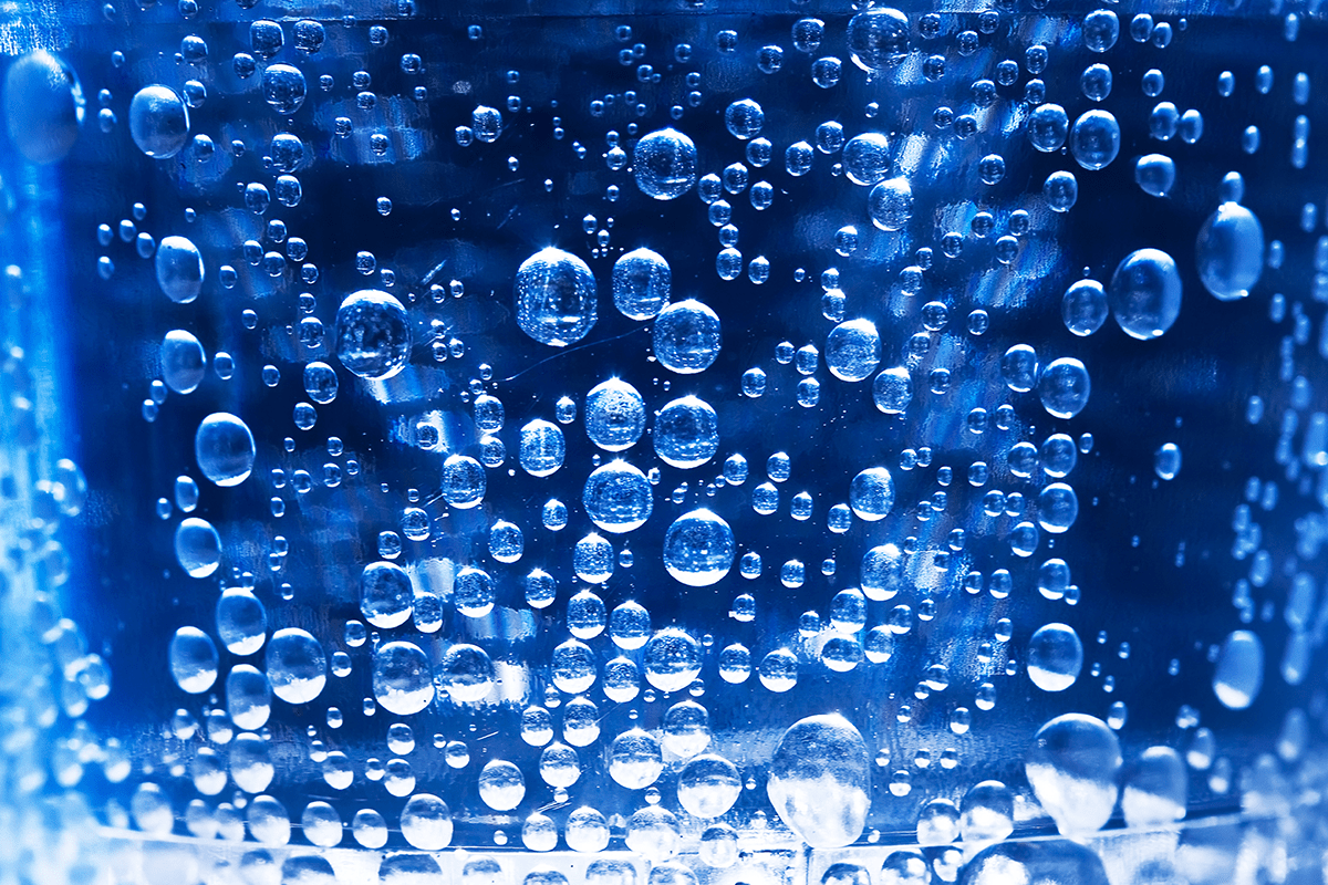 Bubbles in glass of water on blue background