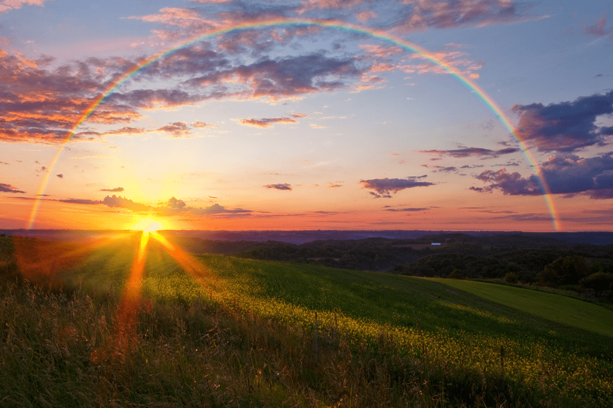 Landscape with rainbow in front of sunset